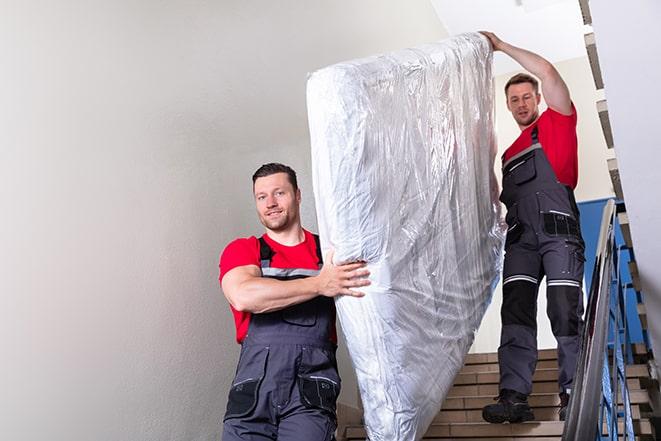 two people carrying a box spring down a staircase in Haymarket, VA